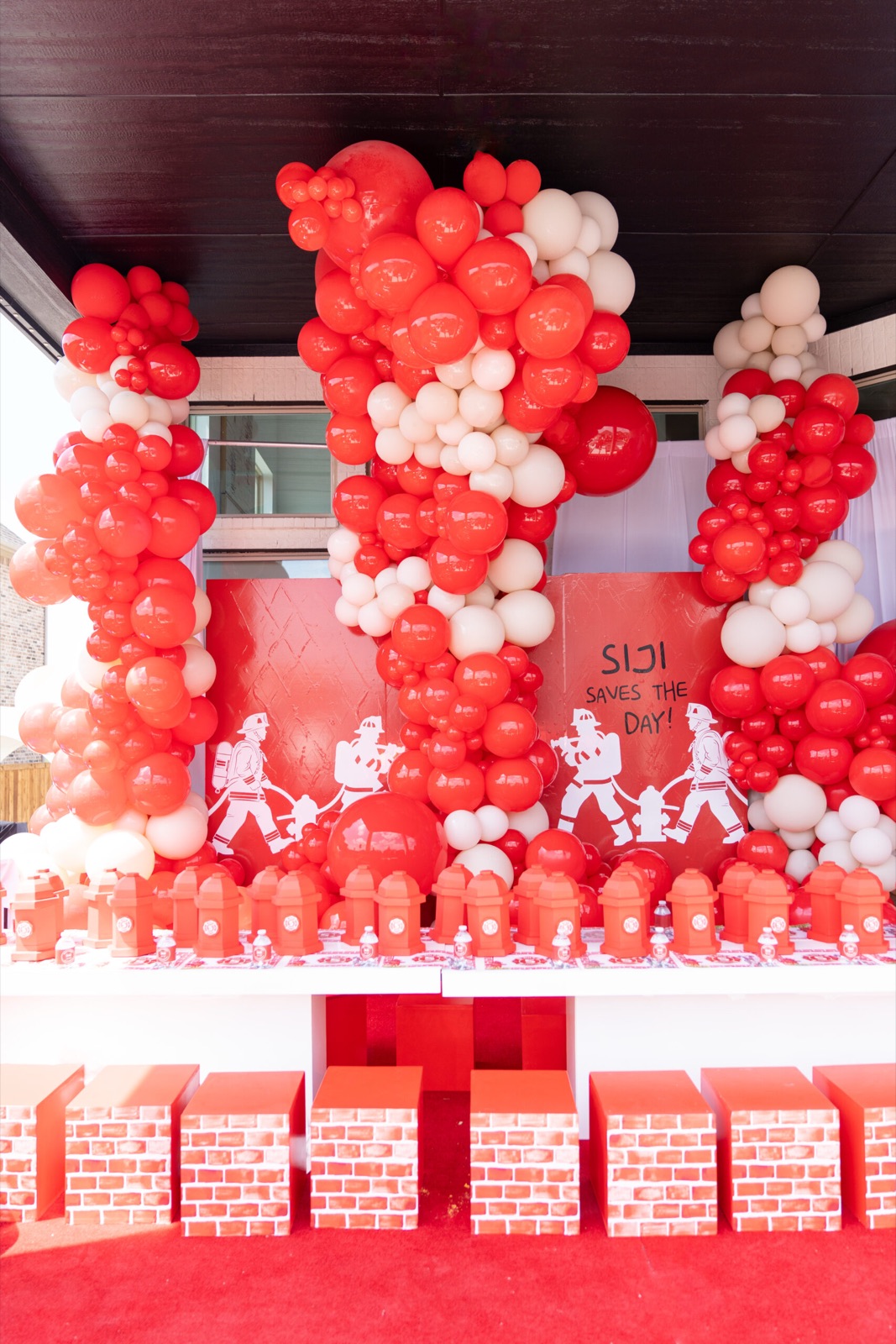 Red and white balloon installation over a dessert table